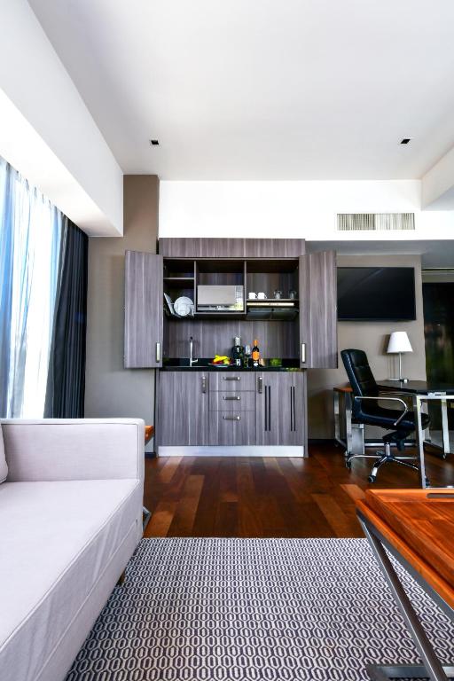 A suite living area facing a compact kitchenette, desk and television.