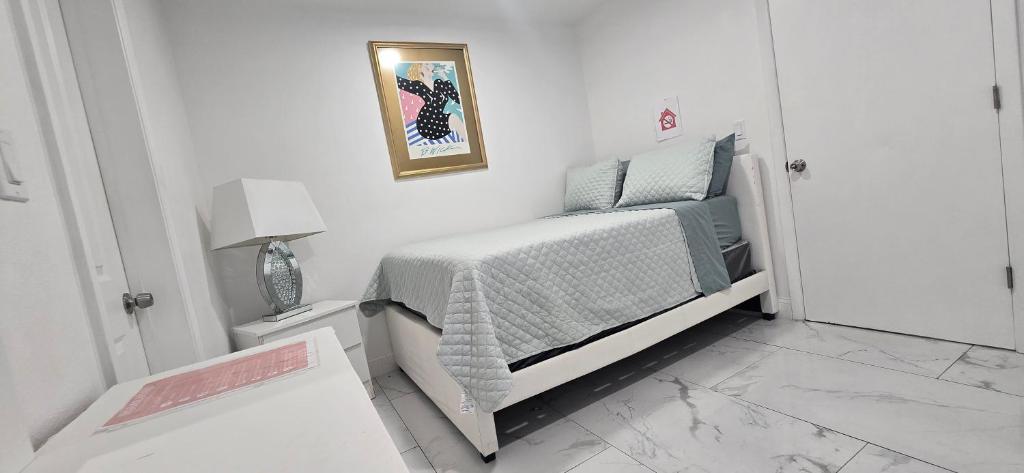 タンパにあるAraly's houseの白い小さなベッドルーム(ベッド1台、ランプ付)