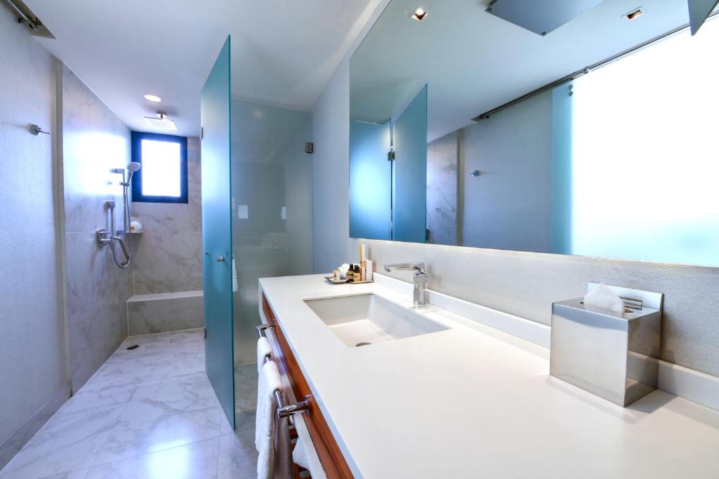 A marble-finished bathroom with a long double vanity and a separate shower area.