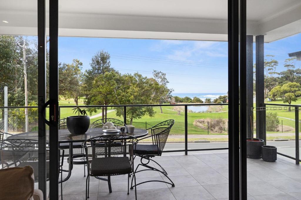 a dining room with a table and chairs on a patio at Ahgunyah Beach House in Mollymook