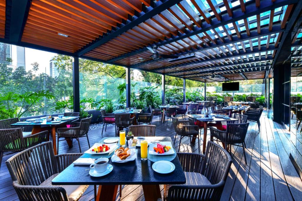 A covered garden terrace laid for breakfast with fruit, pastries, coffee and juice.