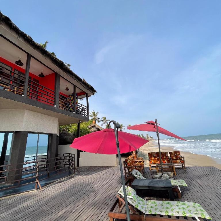 una terrazza con sedie e ombrelloni sulla spiaggia di Shapes Beach House a Kokrobite