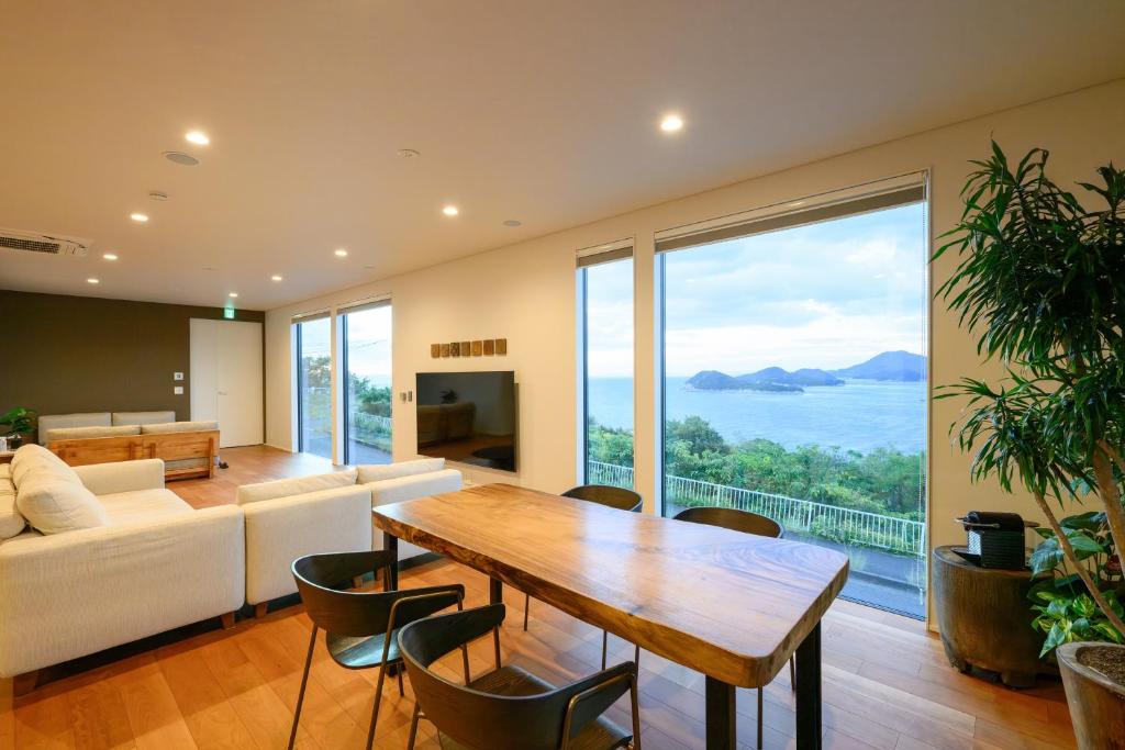 Una sala de estar con una mesa y una gran ventana. en 父母ヶ浜リゾートヴィラ Senja, en Mitoyo