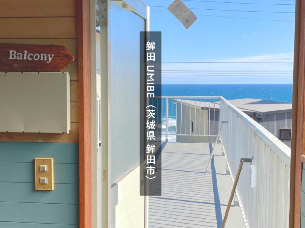 a building with a balcony with the ocean in the background at 海の見える高台に佇む隠れ家宿 #貸別荘 #一棟貸切 #グループや家族旅行におすすめ #テラスで海を眺めながらBBQ #屋内でもBBQ可 #BBQグリル付 #大洗 #鉾田 #umibe in Hokota