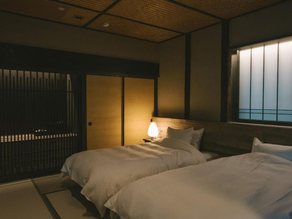 deux lits dans une chambre d'hôtel avec une fenêtre dans l'établissement Ujosouan, à Kyōtango