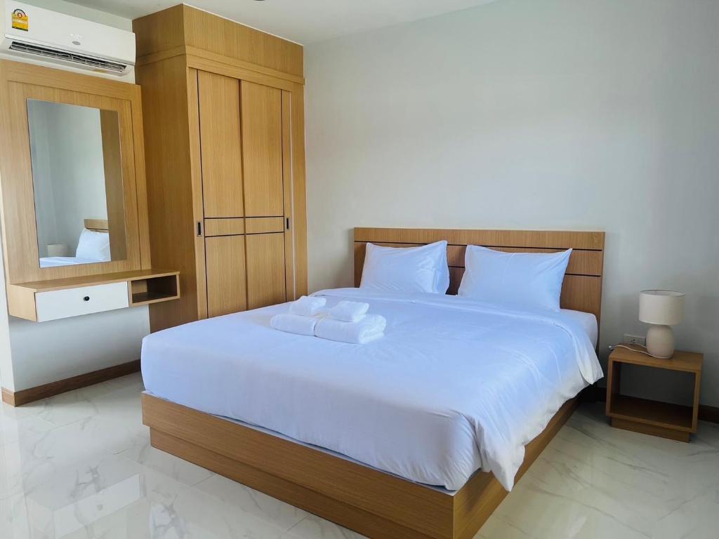 a bedroom with a large bed with white sheets and a mirror at J2 Airport Mansion in Thalang