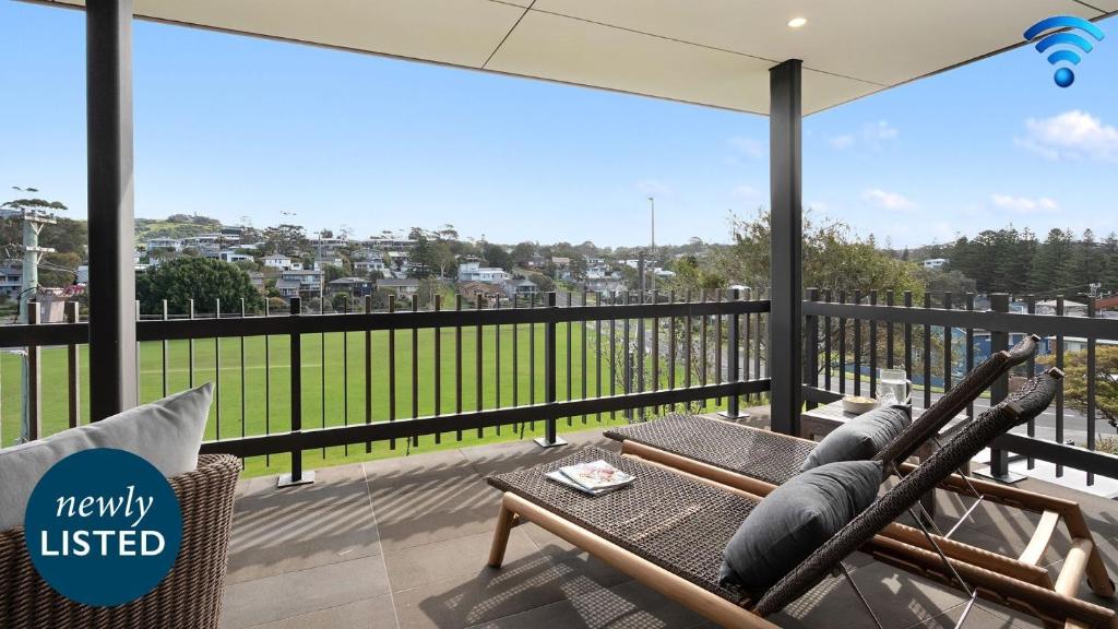 Un balcón con una silla de ratán y una mesa. en Surf N Turf - The Grandstand, en Kiama