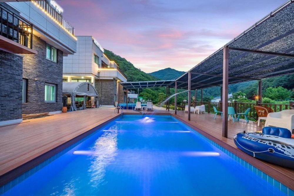 a large blue swimming pool next to a building at Gapyeong Lavita Kids Pool Villa in Yongmunch'ŏn