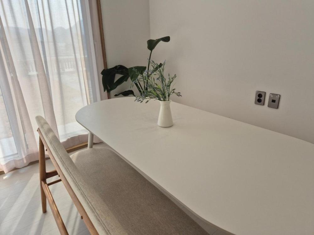 a white table with a vase with a plant on it at Gapyeong Relaxing Pension in Yŏnbyŏn