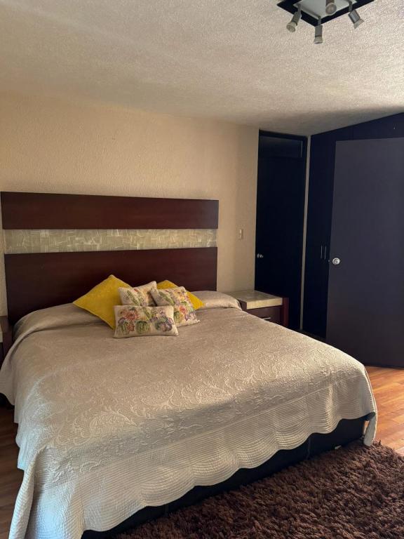 une chambre avec un grand lit blanc avec des oreillers jaunes dans l'établissement Casa Altozano Confort, à Morelia