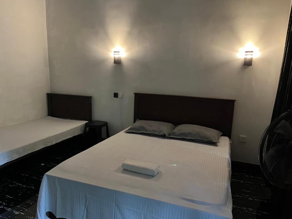 a bedroom with two beds and two lights on the wall at Budget Room By Green House Resort in Sigiriya