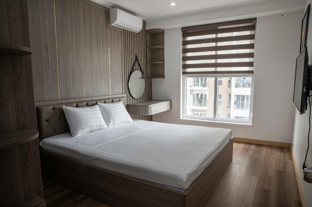 a bedroom with a bed with white sheets and a window at Thảo Aparment Hạ Long in Ha Long