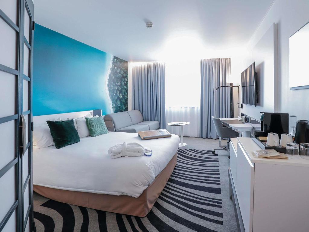une chambre d'hôtel avec un grand lit et un bureau dans l'établissement Novotel Luxembourg Centre, à Luxembourg