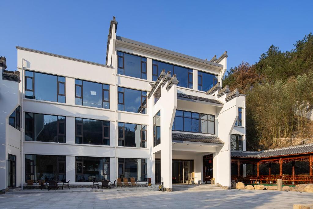 een groot wit gebouw met glazen ramen bij 花筑庐江满山红遍民宿 