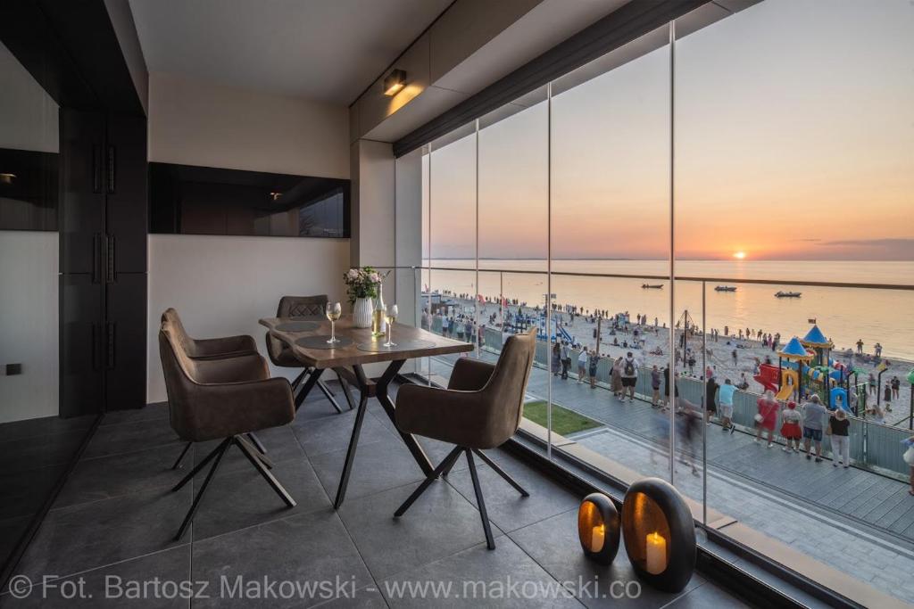 a dining room with a table and chairs and a large window at Baltic Infinity in Międzyzdroje