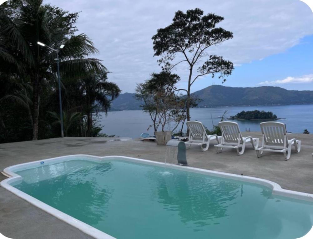 a pool with chairs and a view of the water at Sítio Bela Vista in Angra dos Reis