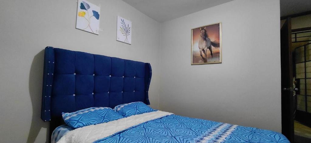 a bed with a blue headboard in a bedroom at Depa Amoblado en Villa María, Excelente ubicación, WiFi, y Parking in Villa María del Trunfo