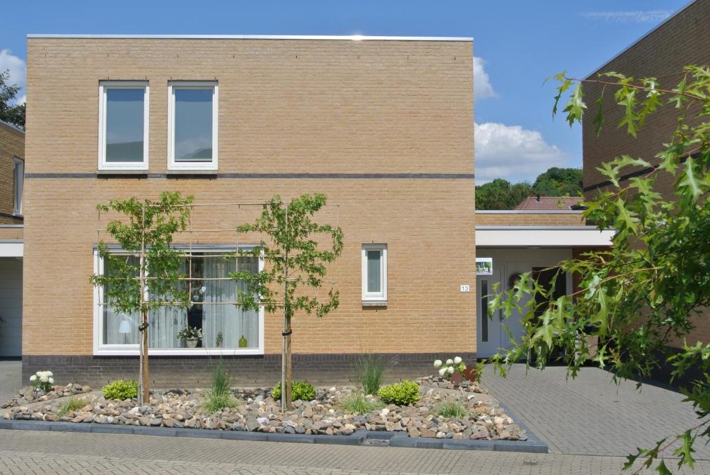 uma casa com duas árvores em frente em B&B Von Clermont Park em Vaals