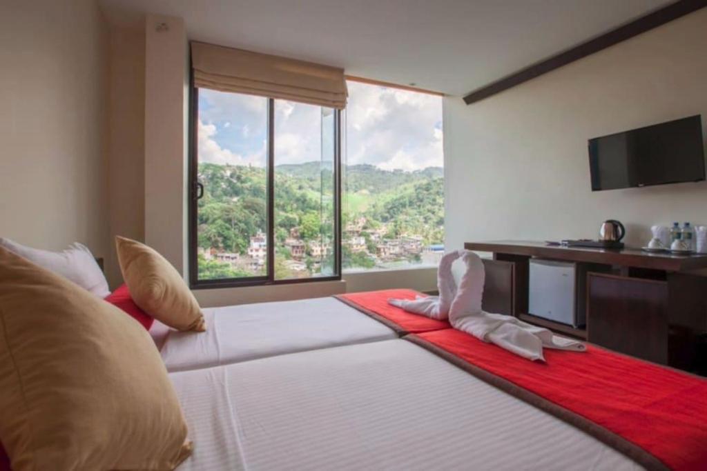 1 dormitorio con 1 cama grande, escritorio y ventana en Oak Ray City Hotel, en Kandy