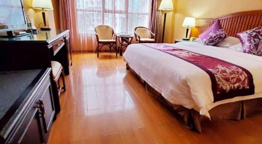 a hotel room with a bed and a table and chairs at Hedong Hotel in Shenzhen