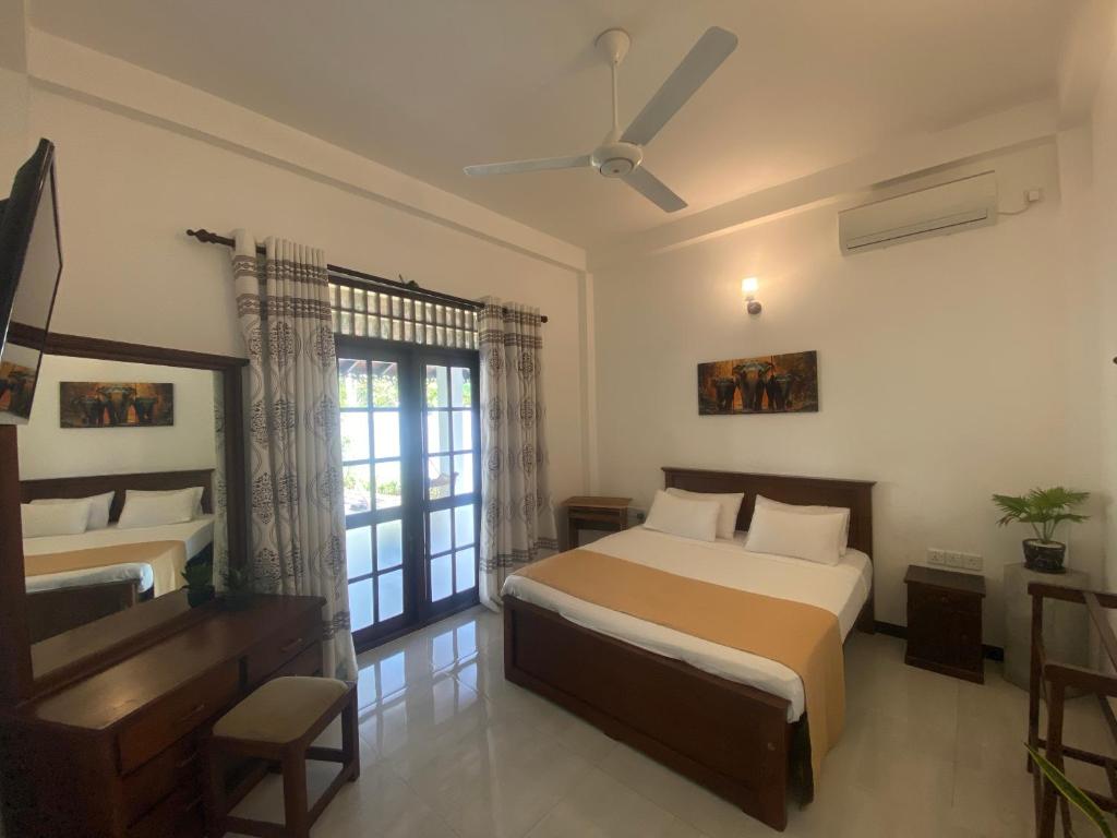 a bedroom with a bed and a desk and a window at Villa 2A in Matara