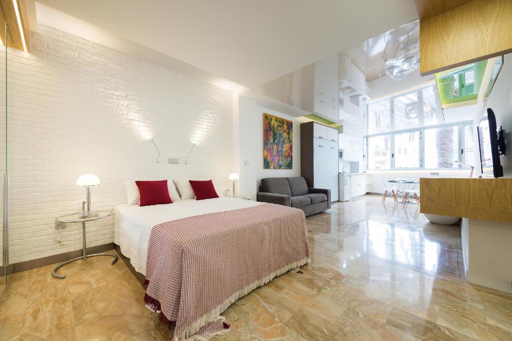 Suites Garden Loft Kandinsky في لاس بالماس دي غران كاناريا: غرفة نوم بسرير كبير وغرفة معيشة