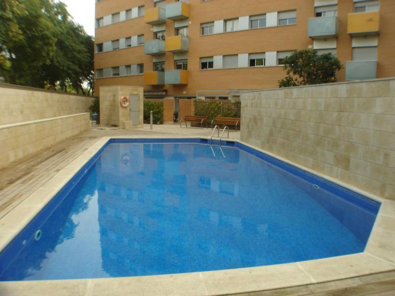 a large blue swimming pool in front of a building at Apartamentos City Beach in Barcelona
