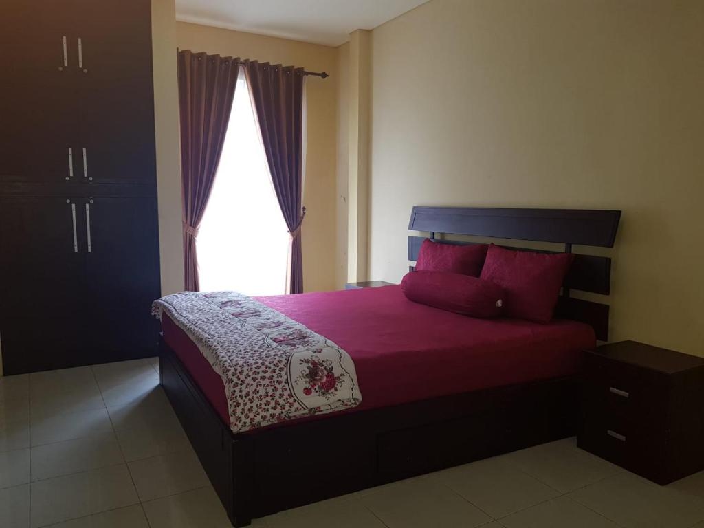 een slaapkamer met een bed met rode kussens en een raam bij Hansel Homestay in Batu