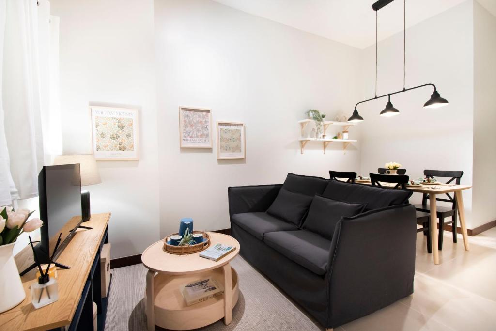 a living room with a black couch and a table at Aston Residences in Manila