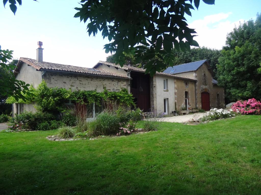 una casa vieja en un patio con césped verde en L´Aveneau, en Le Retail