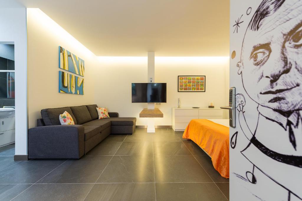 a living room with a couch and a tv at Suites Garden Loft Miro in Las Palmas de Gran Canaria