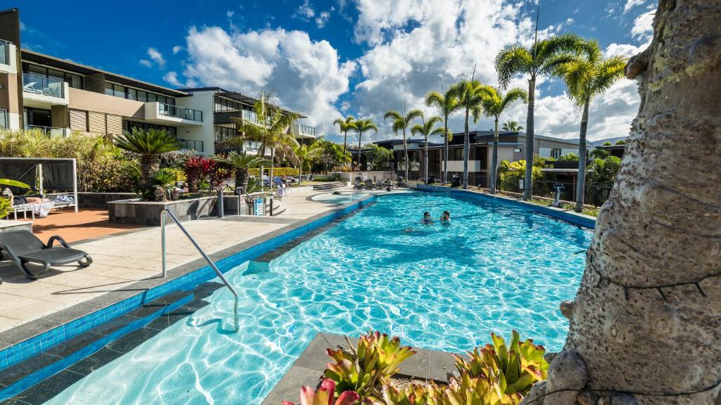una piscina en un resort con palmeras en Mirage Whitsundays, en Airlie Beach