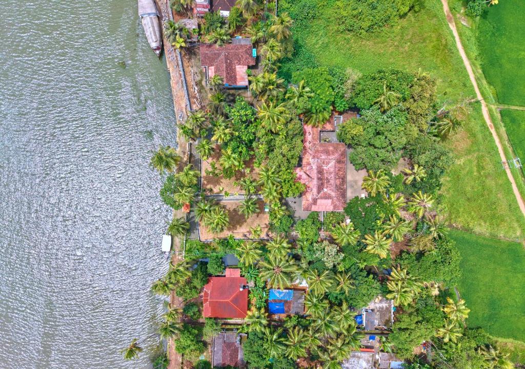an aerial view of a house with trees and water at Cotelac Heritage Lake Resort by VOYE HOMES in Alleppey