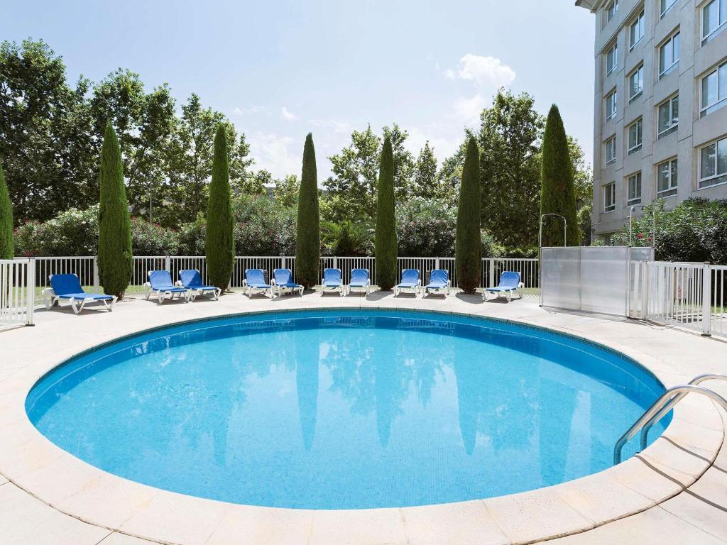 a swimming pool with chairs and a building at Novotel Suites Montpellier Antigone in Montpellier