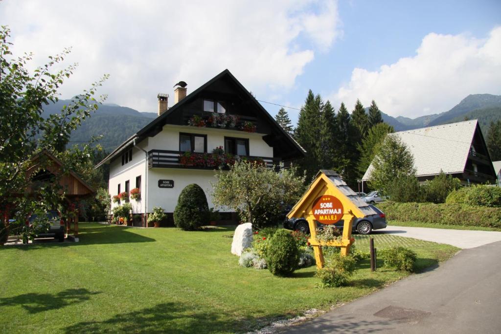 a house with a for sale sign in front of it at Apartments & Rooms Malej in Bohinj