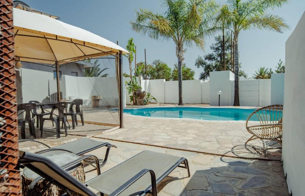 a patio with tables and chairs and a swimming pool at NJ SKY GUESTHOUSE & BOUTIQUE windhoek in Windhoek