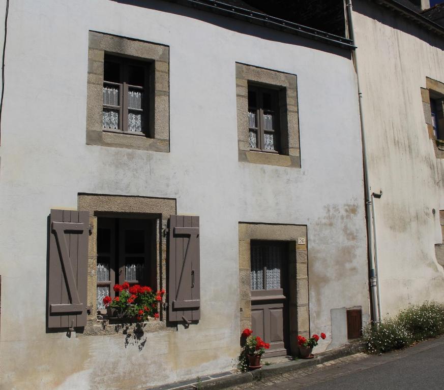 ein weißes Gebäude mit Blumen in den Fenstern in der Unterkunft "Number 26" Town House in Rochefort-en-Terre