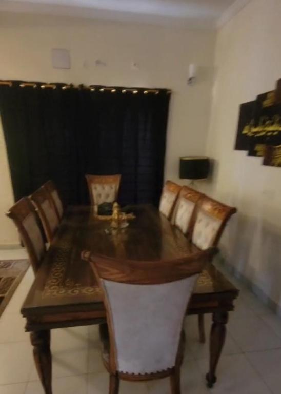 a dining room table with chairs and a wooden table and a window at Luxurious 200 SQY Executive Furnished Villa for Rent in Karachi