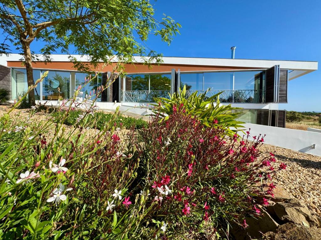 ein Haus am Strand mit Blumen im Vordergrund in der Unterkunft Casas do Moinho, Alentejo Country House in Santa Margarida da Serra
