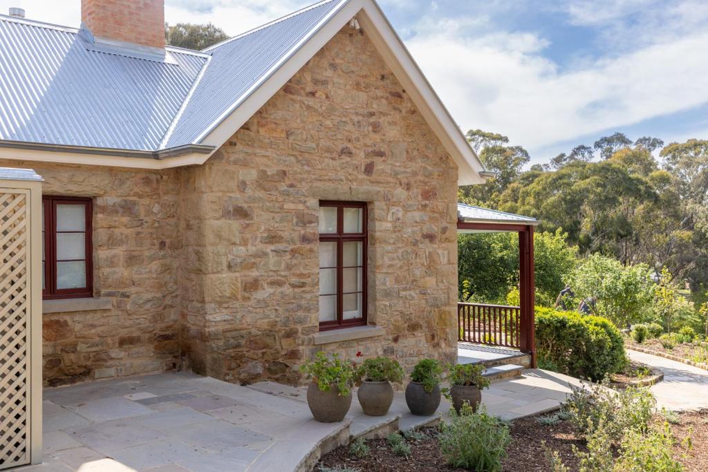 une maison en pierre avec un porche et des plantes en pot dans l'établissement Chester Cottage - Design Haven in Castlemaine, à Castlemaine