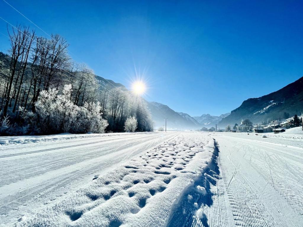una strada innevata con il sole sullo sfondo di Cosy stay near stunning sights, located on main street a Luchsingen