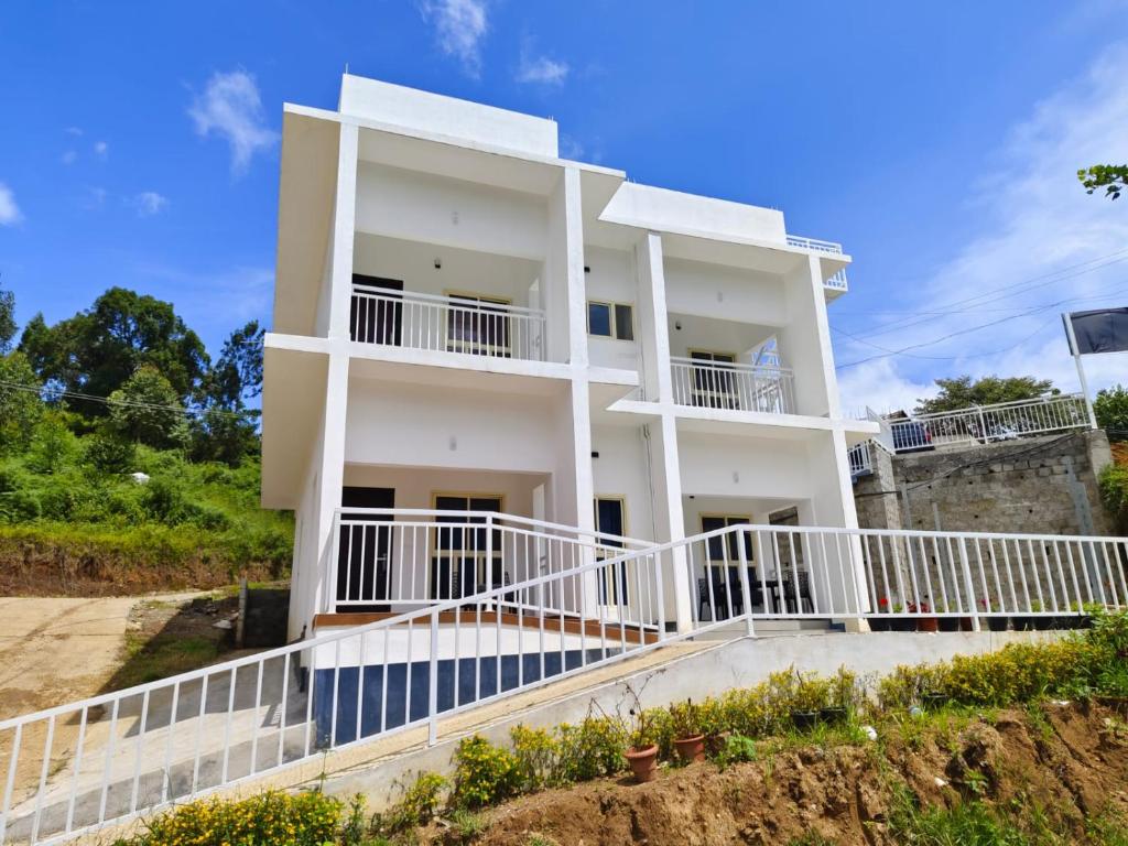 a white house with white railings on a hill at Blue Home Stay in Kanthalloor
