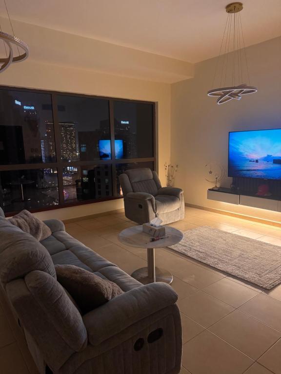 ein Wohnzimmer mit Couch und Fernseher in der Unterkunft Shams Wa Bahar Vacation Homes Rental in Dubai