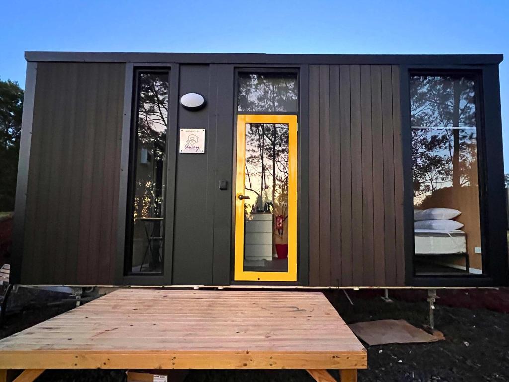 a black tiny house with a yellow door at The Little Refuge by Tiny Away in Dunoon