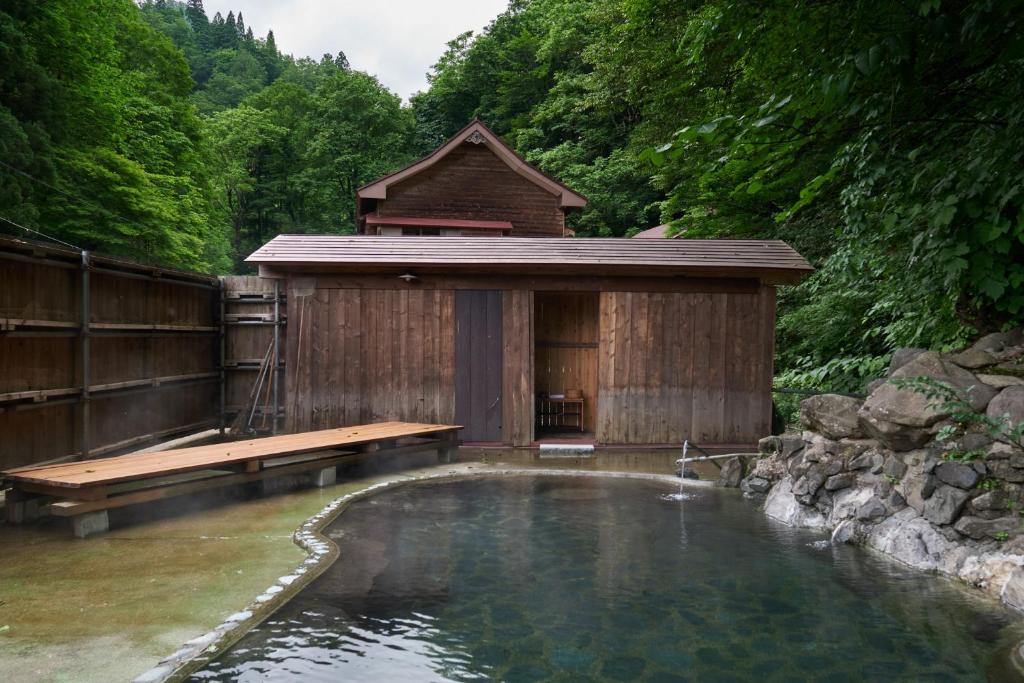 a large pool of water with a wooden building at 森吉山温泉小さな森の湯 in Osarizawakōzan