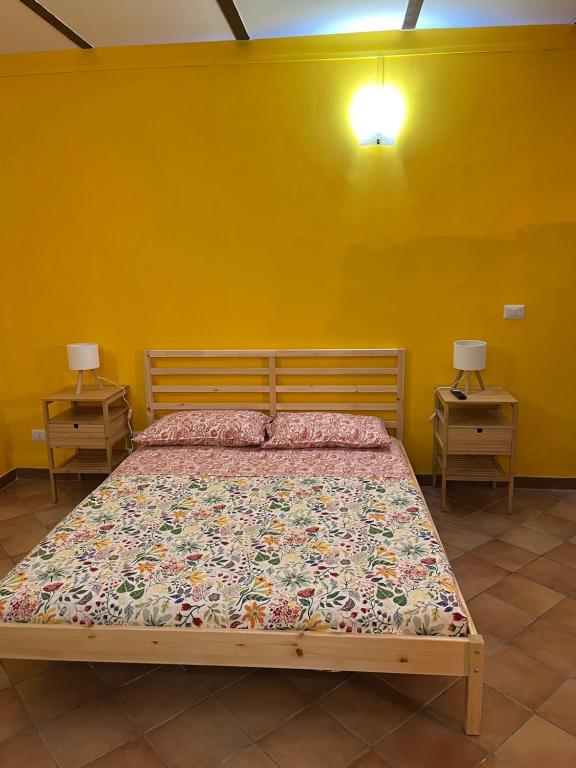 un letto in una stanza gialla con due comodini di B&B il Parco stanza Santa Croce a Oriolo Romano