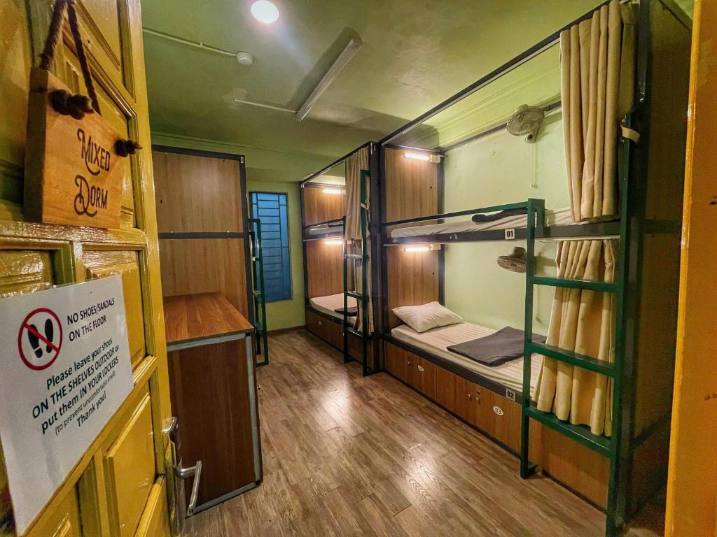 ハノイにあるHanoi Quarter Life Hostelの二段ベッドが3つあり、入り口に看板がある部屋