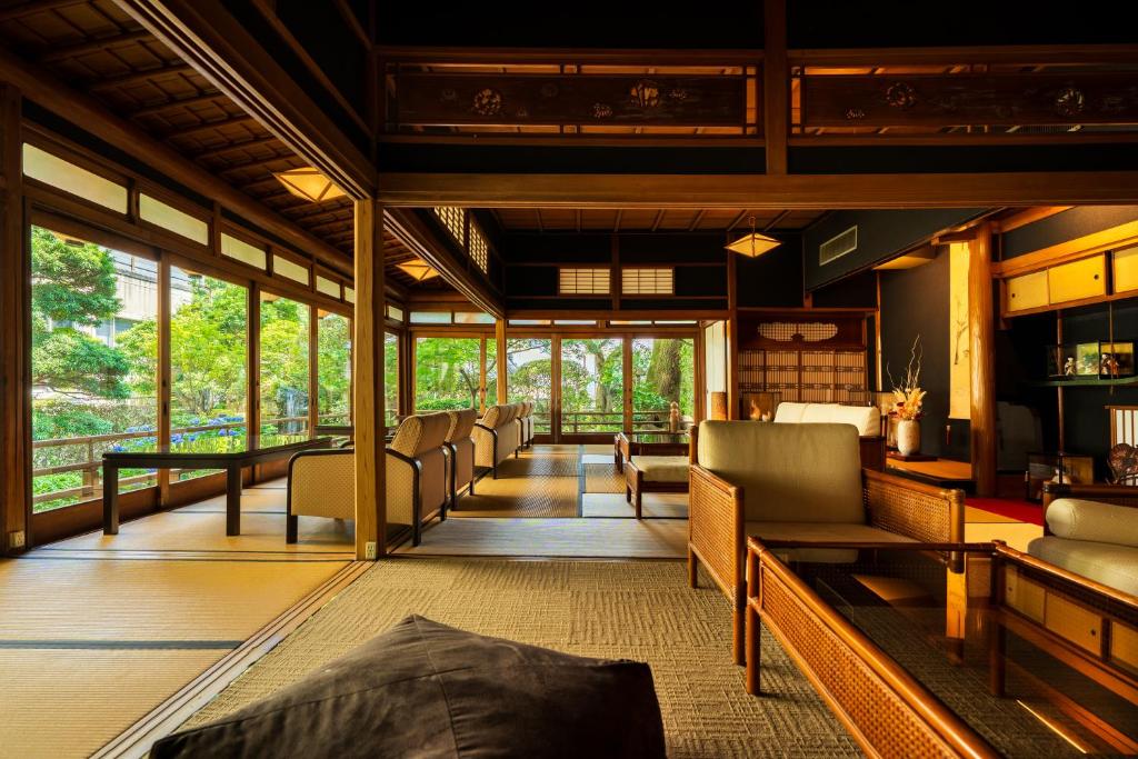 une chambre avec des chaises, une table et des fenêtres dans l'établissement Shiragiku, à Beppu