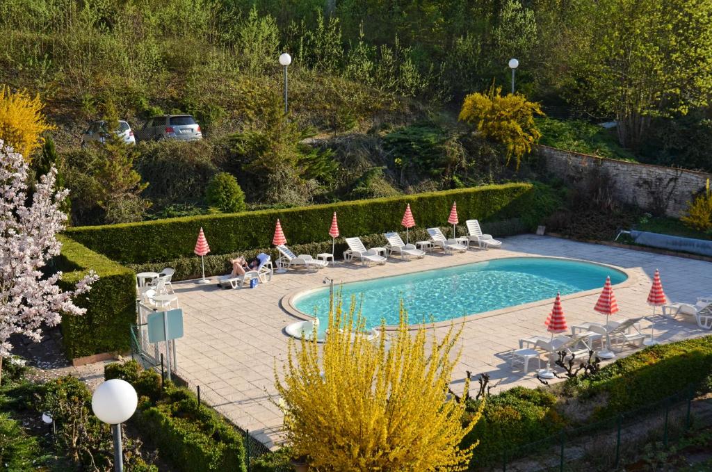 a swimming pool with chairs and umbrellas in a garden at Hôtel et Studios d'Orfeuil in Bourbonne-les-Bains