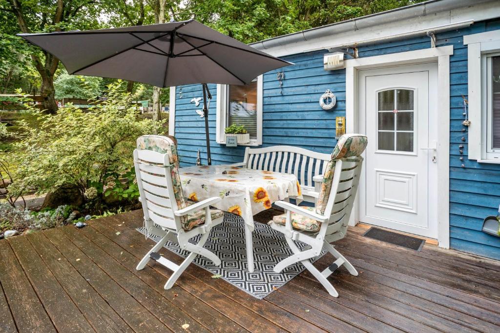 德兰斯克Bungalow 'zur Möwe' Bgl 21的甲板上配有一张桌子和两把椅子及一把遮阳伞